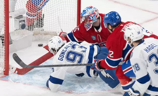 Tampa Bay Lightning's Gage Goncalves (93) scores against Montreal Canadiens goaltender Jakub Dobes, top left, during overtime of Game 6 in the first round of an NHL hockey Stanley Cup playoff series in Montreal, Friday, May 1, 2026. (Christinne Muschi/The Canadian Press via AP)