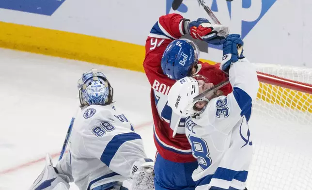Montreal Canadiens' Zachary Bolduc (76) and Tampa Bay Lightning's Brandon Hagel (38) battle for the puck behind Lightning goaltender Andrei Vasilevskiy (88) during the second half of Game 6 in the first round of an NBA basketball playoffs series in Montreal on Friday, May 1, 2026. (Christinne Muschi/The Canadian Press via AP)