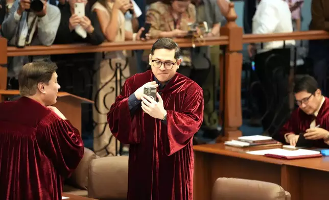Philippine Senator Paolo Benigno "Bam" Aguirre Aquino IV, center, looks at his phone as they convene as an impeachment court for the trial of Vice President Sara Duterte at the Philippine senate, Monday, May 18, 2026, in Pasay, Philippines. (AP Photo/Aaron Favila)