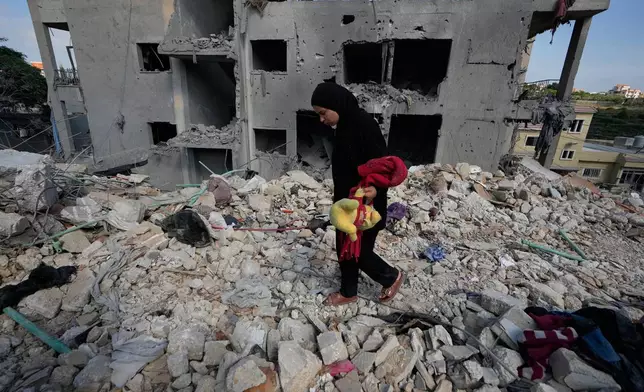 A resident carries belongings as she walks through the rubble of her home destroyed in an Israeli airstrike a day earlier in the southern village of Maarakeh, Lebanon, Wednesday, May 27, 2026. (AP Photo/Mohammed Zaatari)