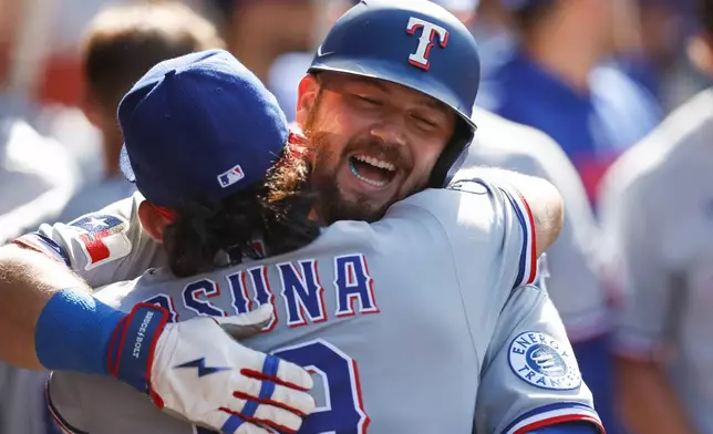 Texas Rangers' Jake Burger, right, is greeted by Texas Rangers' Alejandro Osuna, left, after scoring a home run during the second inning of a baseball game against the Los Angeles Angels, Sunday, May 24, 2026, in Anaheim, Calif. (AP Photo/Caroline Brehman)