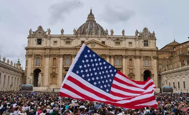 FILE - A flag from the United States waves in the crowd as Pope Leo XIV appears at the central balcony of St. Peter's Basilica for his first Sunday blessing after his election, in St. Peter's Square at the Vatican, Sunday, May 11, 2025. (AP Photo/Bernat Armangue, File)