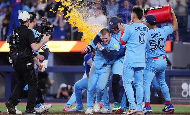 Toronto Blue Jays' Daulton Varsho (left) celebrates his walk-off grand slam against the Tampa Bay Rays with teammates during 10th inning MLB baseball action in Toronto on Wednesday, May 13, 2026. (Nathan Denette/The Canadian Press via AP)