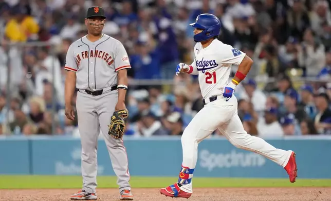 Los Angeles Dodgers' Santiago Espinal, right,heads to second after hitting a solo home run as San Francisco Giants first baseman Rafael Devers watches during the third inning of a baseball game Wednesday, May 13, 2026, in Los Angeles. (AP Photo/Mark J. Terrill)