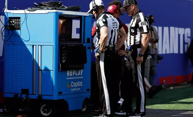 FILE - Referee Shawn Hochuli (83) and back judge Jimmy Russell (82) review a play at the instant replay cart during an NFL football game between the Los Angeles Chargers and the New York Giants, Sunday, Sept. 28, 2025, in East Rutherford, N.J. (AP Photo/Adam Hunger, File)