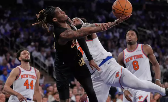 New York Knicks' Mitchell Robinson, center right, fouls Cleveland Cavaliers' Keon Ellis, center left,who goes looks to shoot during the first half of Game 1 in the Eastern Conference finals NBA basketball playoffs series, Tuesday, May 19, 2026, in New York. (AP Photo/Seth Wenig)
