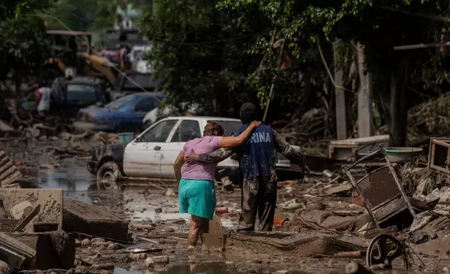 FILE - A Navy officer helps a woman cross a flooded street after heavy rain in Poza Rica, Veracruz state, Mexico, Oct. 12, 2025. (AP Photo/Felix Marquez, File)