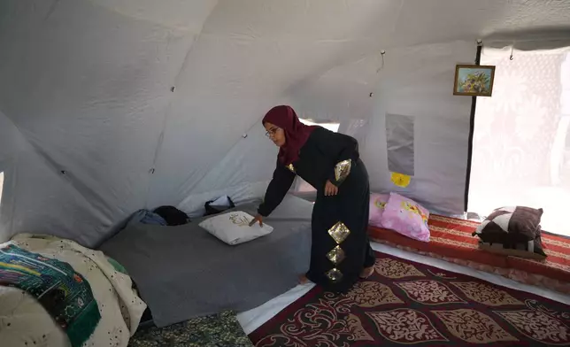 Majida Abu Jarad places a pillow on a bed inside the tent where she lives with her family at a camp for displaced Palestinians in Khan Younis, Wednesday, May 13, 2026. (AP Photo/Abdel Kareem Hana)