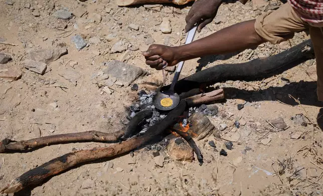 Miners heat processed gold concentrate over an open fire at an artisanal mining site in Dalago Mahas, Sudan's Northern State, Friday, May 8, 2026.(AP Photo/Mohnd Blal)
