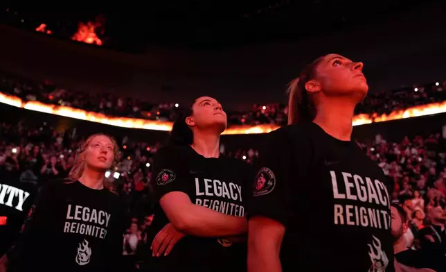Portland Fire center Megan Gustafson, center, stands with guard Sarah Ashlee Barker, right, during player introductions before a WNBA basketball game against the Chicago Sky, Saturday, May 9, 2026, in Portland, Ore. (AP Photo/Jenny Kane)