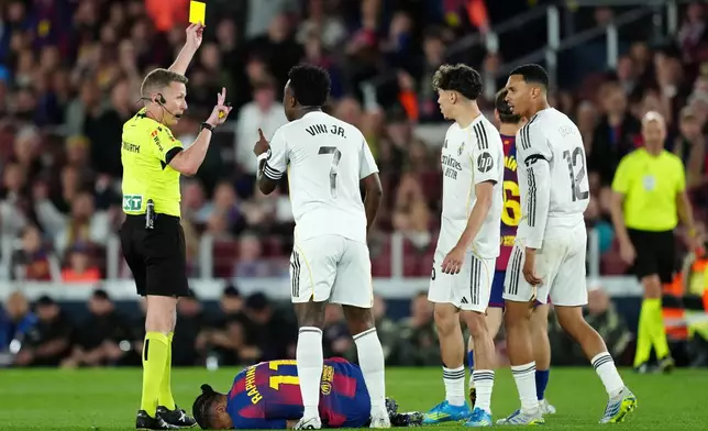Referee Alejandro Jose Hernandez Hernandez shows a yellow card to Real Madrid's Trent Alexander-Arnold, right, during the Spanish La Liga soccer match between FC Barcelona and Real Madrid in Barcelona, Spain, Sunday, May 10, 2026. (AP Photo/Joan Mateu Parra)
