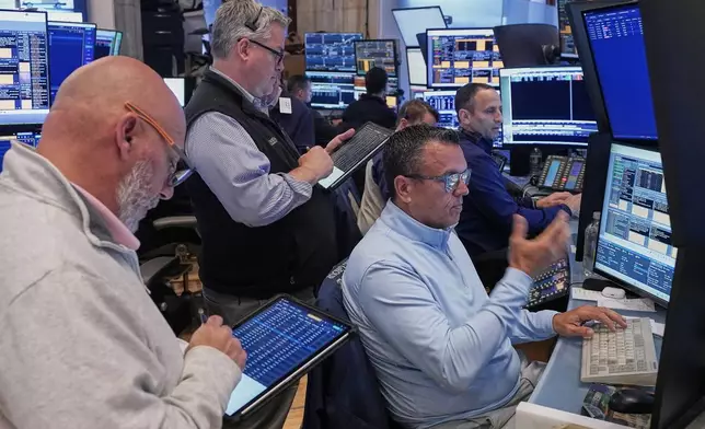 Robert Finnerty, Jr., foreground right, works with colleagues on the floor of the New York Stock Exchange, Thursday, May 7, 2026. (AP Photo/Richard Drew)