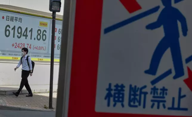 A person walks in front of an electronic stock board showing Japan's Nikkei index at a securities firm Thursday, May 7, 2026, in Tokyo. (AP Photo/Eugene Hoshiko)
