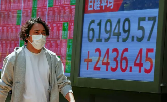 A person walks in front of an electronic stock board showing Japan's Nikkei index at a securities firm Thursday, May 7, 2026, in Tokyo. (AP Photo/Eugene Hoshiko)