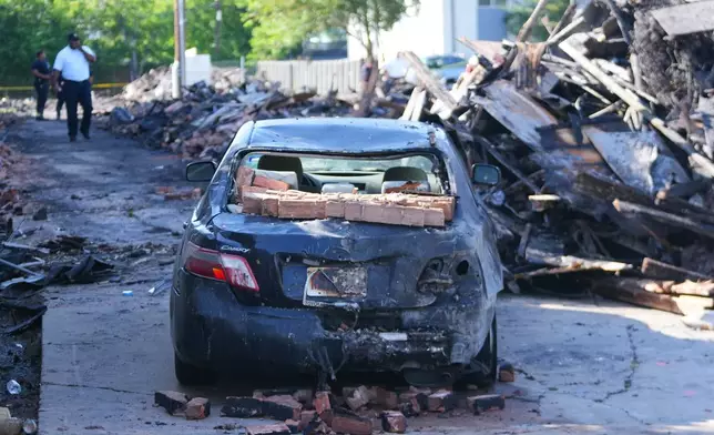 A vehicle is seen damaged following an apartment complex fire, Friday, May 29, 2026, in Dallas. (AP Photo/Julio Cortez)