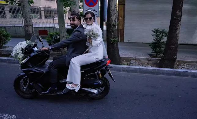 A groom and bride ride on their motorbike in northern Tehran, Iran, Friday, May 1, 2026. (AP Photo/Vahid Salemi)