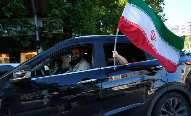 A child holds an Iranian flag through the window of a vehicle in northern Tehran, Iran, Friday, May 1, 2026. (AP Photo/Vahid Salemi)