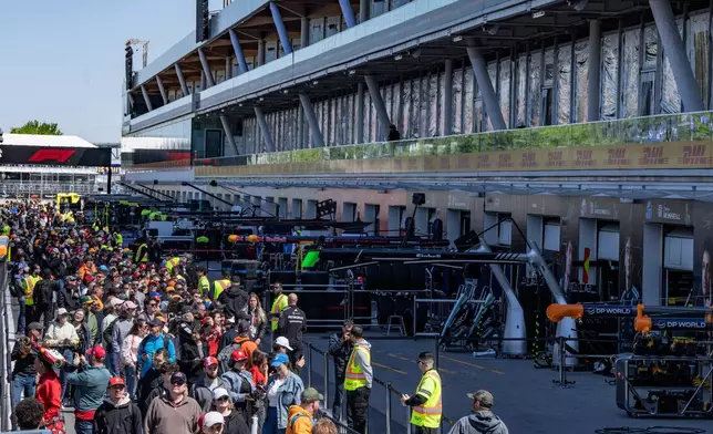 Race fans walk through pit lane during the open house at the F1 Canadian Grand Prix auto race, Thursday, May 21, 2026, in Montreal. (Christinne Muschi/The Canadian Press via AP)