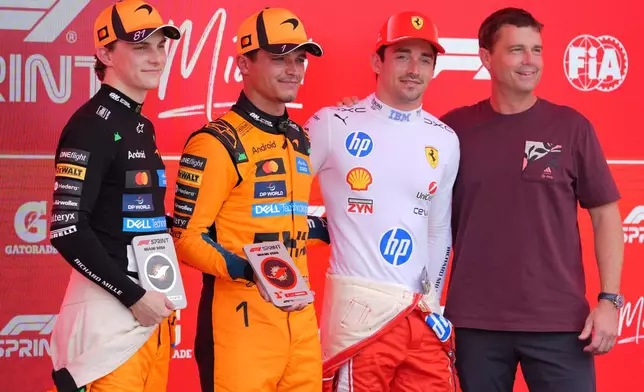 Astronaut Reid Wiseman, right, poses for a photo with (from left) third place finisher McLaren driver Oscar Piastri of Australia, first place finisher McLaren driver Lando Norris of Britain, and third place finisher Ferrari driver Charles Leclerc of Monaco after a sprint auto race at the Miami Formula One Grand Prix, Saturday, May 2, 2026, in Miami Gardens, Fla. (AP Photo/Rebecca Blackwell)