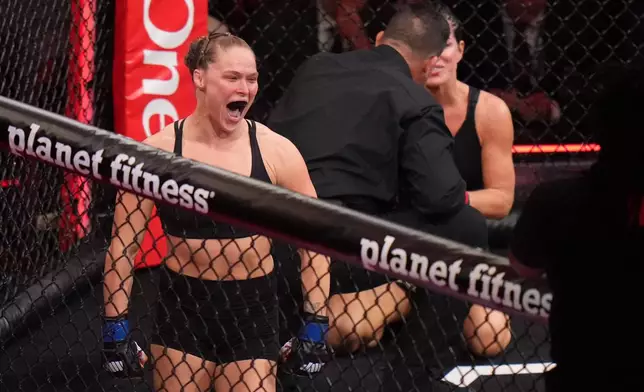 Ronda Rousey, of the United States, left, celebrates after defeating Gina Carano, of the United States, right, in their featherweight mixed martial arts fight Saturday, May 16, 2026, in Inglewood, Calif. (AP Photo/Jae C. Hong )