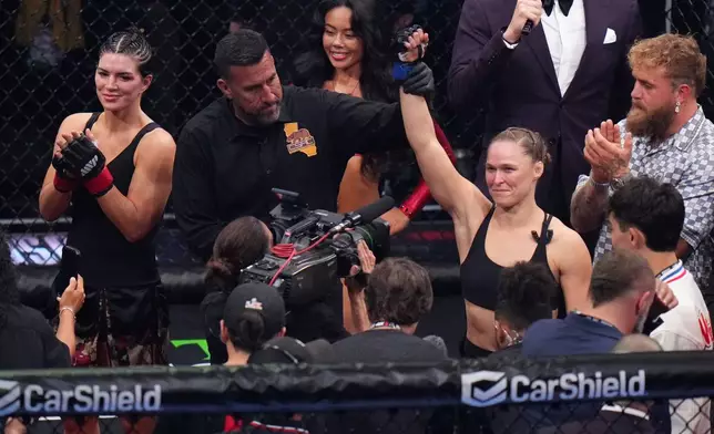 Ronda Rousey, of the United States, center, celebrates after defeating Gina Carano, of the United States, left, in their featherweight mixed martial arts fight Saturday, May 16, 2026, in Inglewood, Calif. (AP Photo/Jae C. Hong )