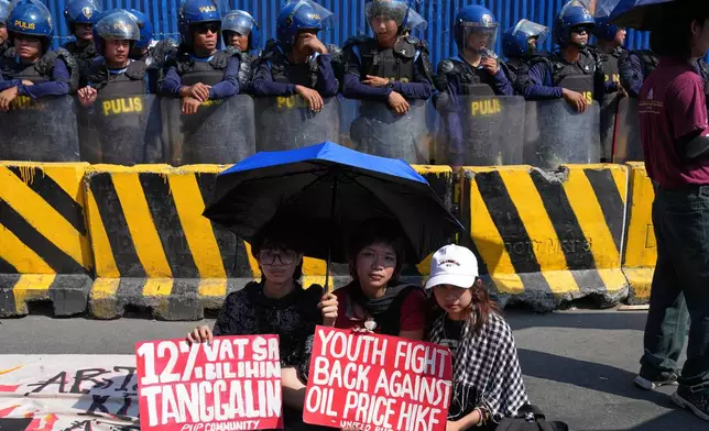 FILE - Protesters hold slogans beside police during a rally by transport workers and activists protesting the rise in oil prices on March 27, 2026, near the Malacanang presidential palace in Manila, Philippines. (AP Photo/Aaron Favila, File)