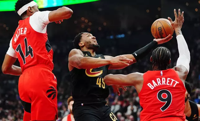 Cleveland Cavaliers' Donovan Mitchell (45) shoots as Toronto Raptors' Ja'kobe Walter (14) and RJ Barrett (9) defend during the first half of Game 6 in the first round of an NBA basketball playoffs series in Toronto on Friday, May 1, 2026. (Nathan Denette/The Canadian Press via AP)