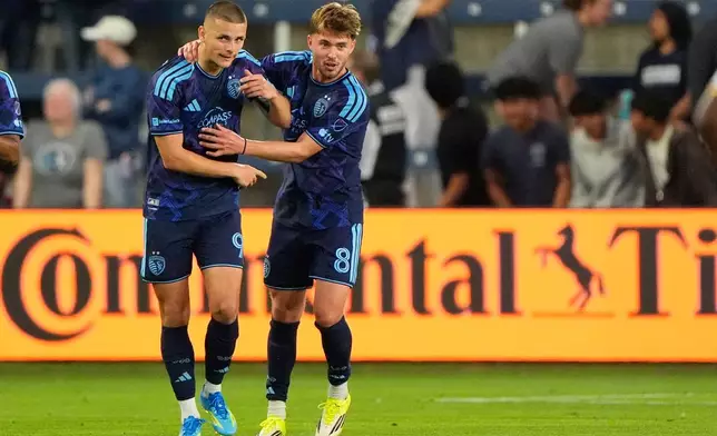 Sporting Kansas City forward Dejan Joveljic (9) and defender Jake Davis (8) celebrate after Joveljic scored a goal during the first half of an MLS soccer match against LA Galaxy, Wednesday, May 13, 2026, in Kansas City, Kan. (AP Photo/Charlie Riedel)