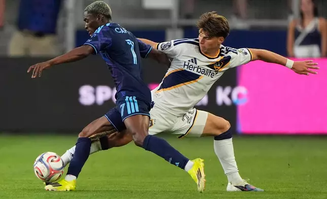 Sporting Kansas City forward Capita (7) and LA Galaxy forward Harbor Miller, right, battle for the ball during the first half of an MLS soccer match Wednesday, May 13, 2026, in Kansas City, Kan. (AP Photo/Charlie Riedel)