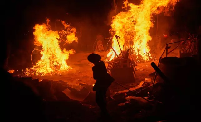 An ultra-Orthodox Jewish youth stands next to bonfires during Lag BaOmer, a holiday traditionally celebrated with bonfires, music, and gatherings, in Jerusalem, Monday, May 4, 2026. (AP Photo/Ohad Zwigenberg)