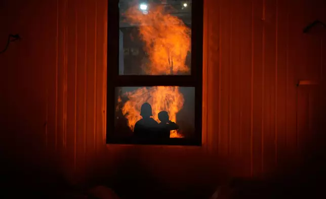 Ultra-Orthodox Jewish boys are reflected in a window as they stand around a bonfire during Lag BaOmer, a holiday traditionally celebrated with bonfires, music, and gatherings, in Jerusalem, Monday, May 4, 2026. (AP Photo/Ohad Zwigenberg)