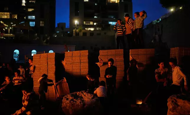Ultra-Orthodox Jewish boys stand around a bonfire during Lag BaOmer, a holiday traditionally celebrated with bonfires, music, and gatherings, in Jerusalem, Monday, May 4, 2026. (AP Photo/Ohad Zwigenberg)