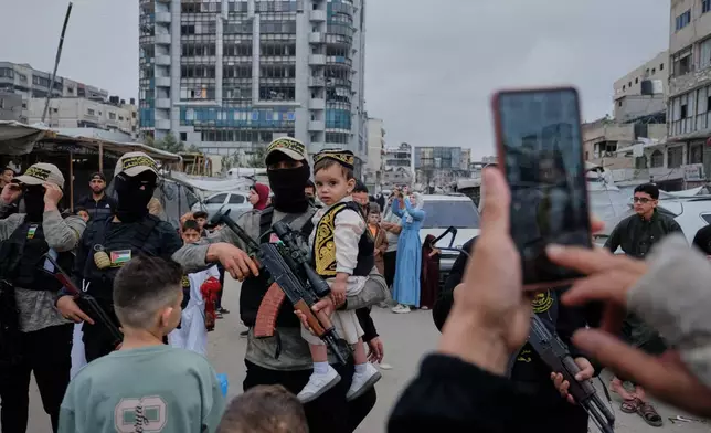 Palestinians take photos with Islamic Jihad militants as they gather for Eid al-Adha prayers in Gaza City Wednesday, May 27, 2026. (AP Photo/Jehad Alshrafi)