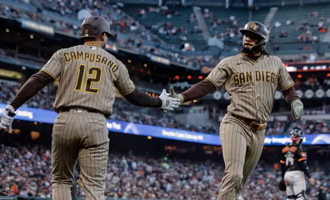 San Diego Padres' Luis Campusano (12) high-fives Fernando Tatis Jr. (23) after he scored on a hit by Nick Castellanos in the fourth inning of a baseball game against the San Francisco Giants in San Francisco on Tuesday, May 5, 2026. (Carlos Avila Gonzalez/San Francisco Chronicle via AP)