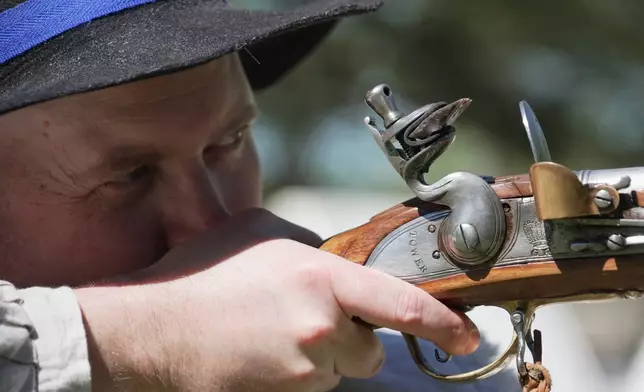 A.J. Drake, a historic interpreter, aims his Brown Bess flintlock replica musket during a Revolutionary War event in Halifax, N.C., on April 10, 2026. (AP Photo/Allen G. Breed)