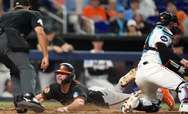 Baltimore Orioles' Pete Alonso, center, scores past Miami Marlins catcher Liam Hicks, right, on a single by Leody Taveras, during the ninth inning of a baseball game, Tuesday, May 5, 2026, in Miami. (AP Photo/Rebecca Blackwell)