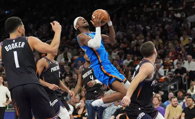 Oklahoma City Thunder guard Shai Gilgeous-Alexander, center drives to the basket between Phoenix Suns guard Devin Booker (1) and Suns guard Collin Gillespie, right, during the second half of Game 4 in a first-round NBA playoffs basketball series, Monday, April 27, 2026, in Phoenix. (AP Photo/Ross D. Franklin)