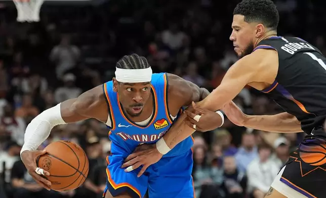 Oklahoma City Thunder guard Shai Gilgeous-Alexander, left, protects the ball from Phoenix Suns guard Devin Booker during the second half of Game 4 in a first-round NBA playoffs basketball series, Monday, April 27, 2026, in Phoenix. (AP Photo/Ross D. Franklin)