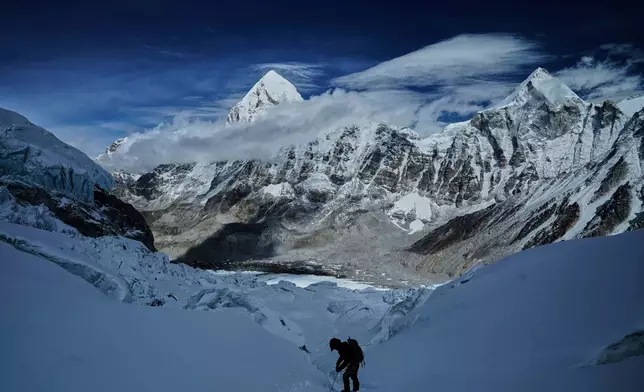 FILE - Mount Pumori, center left, looms in the background as a mountaineer negotiates Khumbu Icefall to descend to Everest Base Camp, in Nepal, May 4, 2025. (AP Photo/Pasang Rinzee Sherpa, File)