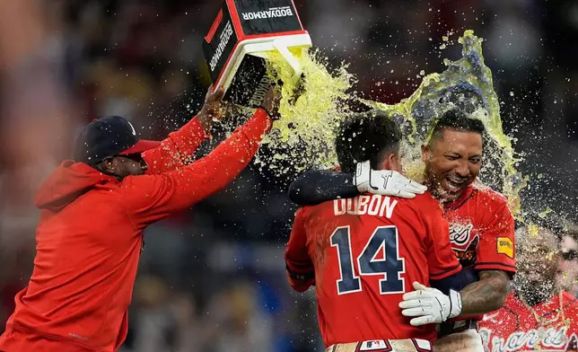 Atlanta Braves' Chadwick Tromp embraces Mauricio Dubón (14) after hitting the game-winning RBI-Single in the 11th inning of a baseball game against the Washington Nationals, Friday, May 22, 2026, in Atlanta. (AP Photo/Mike Stewart)