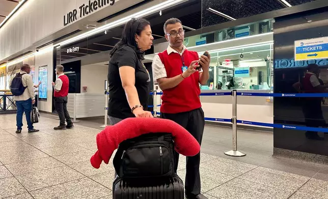 Long Island Rail Road employee Sujit Saha helps a passenger find her train at New York's Penn Station, Tuesday, May 19, 2026. (AP Photo/Richard Drew)