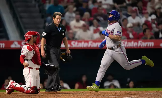 New York Mets catcher Francisco Alvarez, right, scores on a two RBI single by Marcus Semien as Los Angeles Angels catcher Travis D'Arnaud kneels at the plate during the sixth inning of a baseball game Friday, May 1, 2026, in Anaheim, Calif. (AP Photo/Mark J. Terrill)