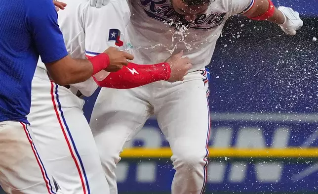 Texas Rangers' Ezequiel Duran, right, celebrates after his walkoff single with teammate Jake Burger, second from left, in the ninth inning of a baseball game against the Kansas City Royals, Saturday, May 30, 2026, in Arlington, Texas. (AP Photo/LM Otero)