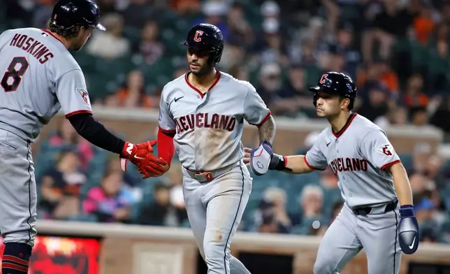 Cleveland Guardians' Brayan Rocchio, center, and Steven Kwan, right, celebrate with Rhys Hoskins (8) after scoring against the Detroit Tigers on a double by Jose Ramirez during the sixth inning of a baseball game, Monday, May 18, 2026, in Detroit. (AP Photo/Duane Burleson)