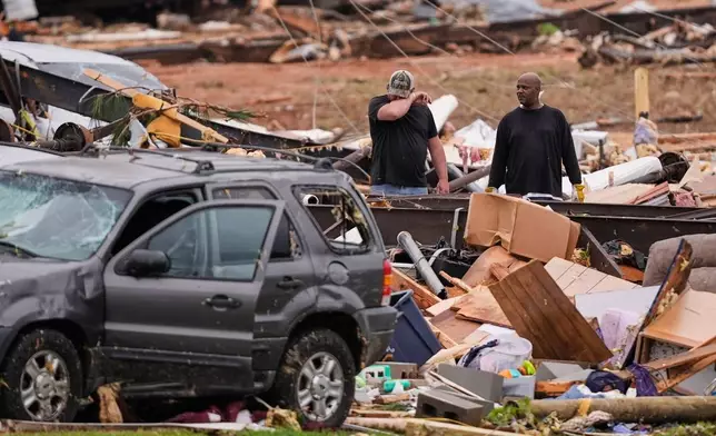 People stand among debris at Gene's Mobile Home Supply, a trailer park in Bogue Chitto, Miss., Thursday, May, 7, 2026, after a tornado cut across the state. (AP Photo/Gerald Herbert)