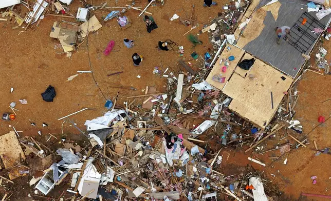 People walk among debris at Gene's Mobile Home Supply, a trailer park in Bogue Chitto, Miss., Thursday, May, 7, 2026, after a tornado cut across the state. (AP Photo/Gerald Herbert)