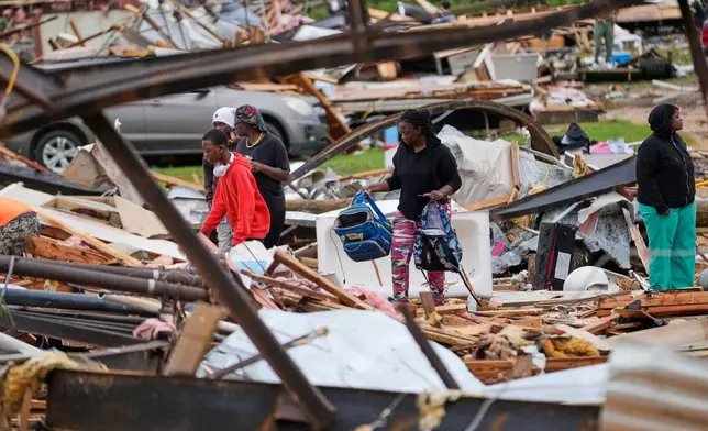 People stand among debris at Gene's Mobile Home Supply, a trailer park in Bogue Chitto, Miss., Thursday, May, 7, 2026, after a tornado cut across the state. (AP Photo/Gerald Herbert)