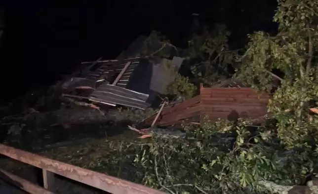 In this frame grab from video taken by WDAM, damaged trees and a house or structure following a storm that tore through part of Lamar County, Mississippi, Wednesday, May 6, 2026. (WDAM via AP)