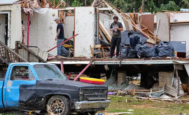 People stand among debris at Gene's Mobile Home Supply, a trailer park in Bogue Chitto, Miss., Thursday, May, 7, 2026, after a tornado cut across the state. (AP Photo/Gerald Herbert)