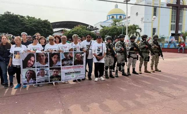 People searching for migrants who vanished in late 2024 along a maritime smuggling route to the U.S. pose with photos of their missing loved ones in Mazatan, Chiapas state, Mexico, Saturday, May 9, 2026. (AP Photo/Edgar H. Clemente)